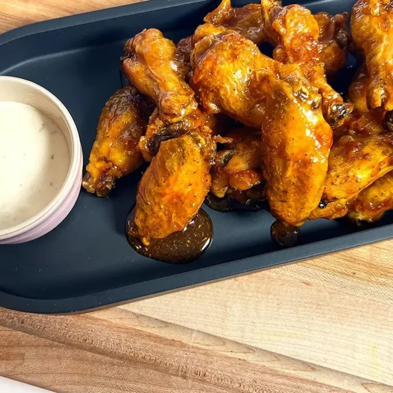 Knusprige Hähnchenflügel mit würziger Sauce und einer Beilage aus Dipsauce.